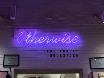 Otherwise Bookstore sign lit up in purple at night