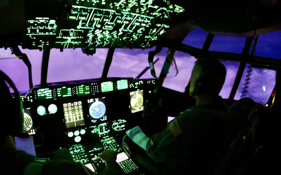 Two so-called Hurricane Hunters are seen at the cockpit of their plane with a darkening sky visible outside their windows.