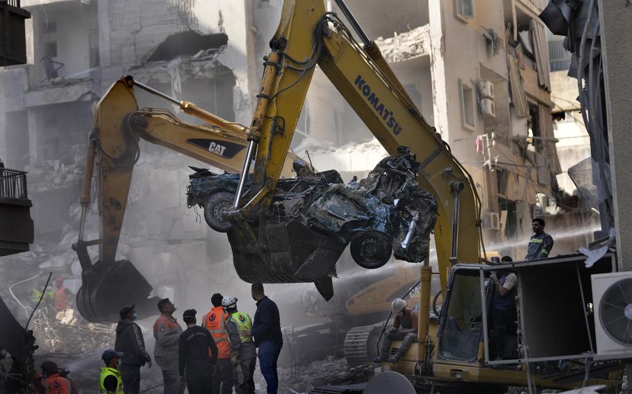 An excavator removes a destroyed car as rescue workers gather at the site of an Israeli airstrike that hit central Beirut, Lebanon, Saturday, Nov. 23, 2024.