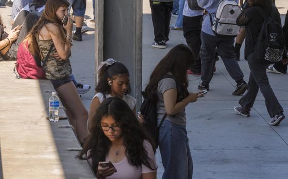 FILE - Students use their cellphones as they leave for the day the Ramon C. Cortines School of Visual and Performing Arts High School in downtown Los Angeles, Aug. 13, 2024. (AP Photo/Damian Dovarganes, File)