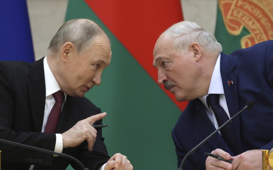 Valadimir Putin leans in to speak with Alexander Lukashenko.