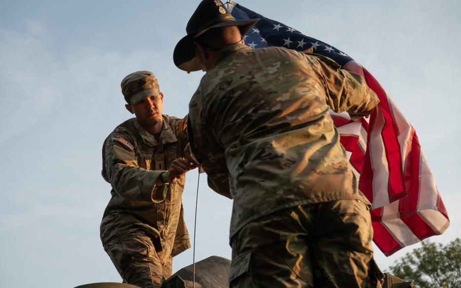 Soldiers fasten an American flag to a vehicle at the Tanks in Town parade in Mons, Belgium