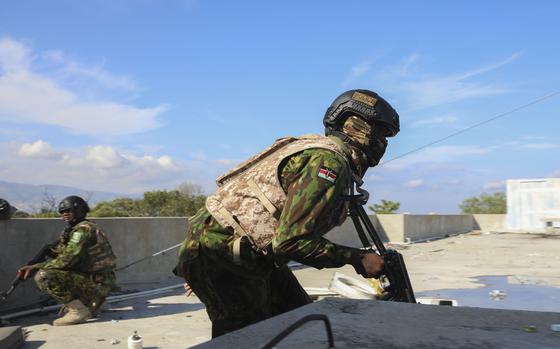 A view from the side of Kenyan police officer, weapon pointed down, looking for cover from gunfire.