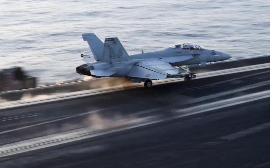 A fighter jets speeds down the runway aboard a carrier.