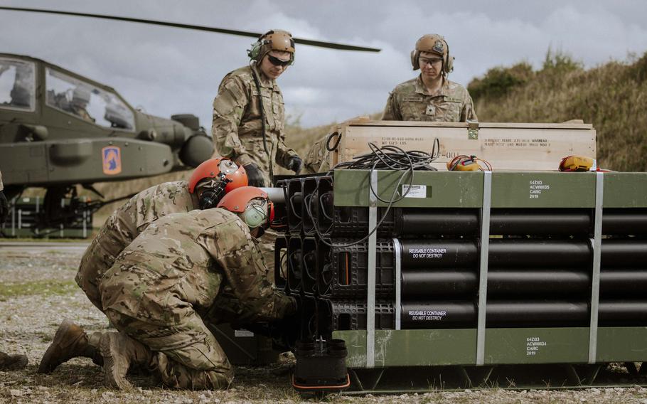 Soldiers with the 12th Combat Aviation Brigade prepare to load rockets into idling Apache helicopters at a forward arming and refueling point at the Grafenwoehr Training Area in Germany, on Sept. 24, 2024.