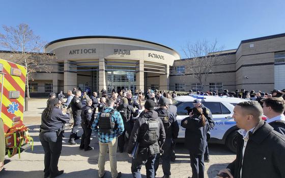 A crowd of students and emergency personnel gathered outside of a high school.