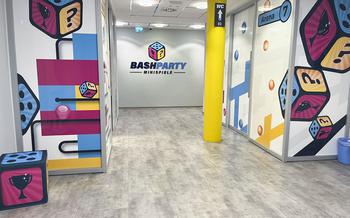 Blue, yellow, and pink paintings of dice and other rectangular shapes accompany the BashParty logo in a corridor.