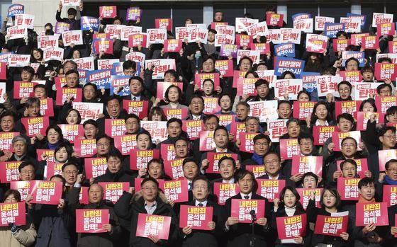 At a news conference, a group of people hold signs that read “Impeach Yoon Suk Yeol.”