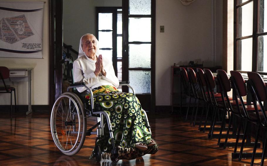 Sister Inah Inah Canabarro is in a wheelchair puts her hands together in prayer.