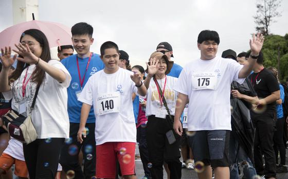 Athletes wave as they walk in a parade. 