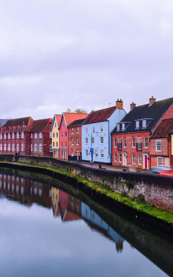 View of colorful historical houses in the center of Norwich, England, UK during the sunset with cloudy sky