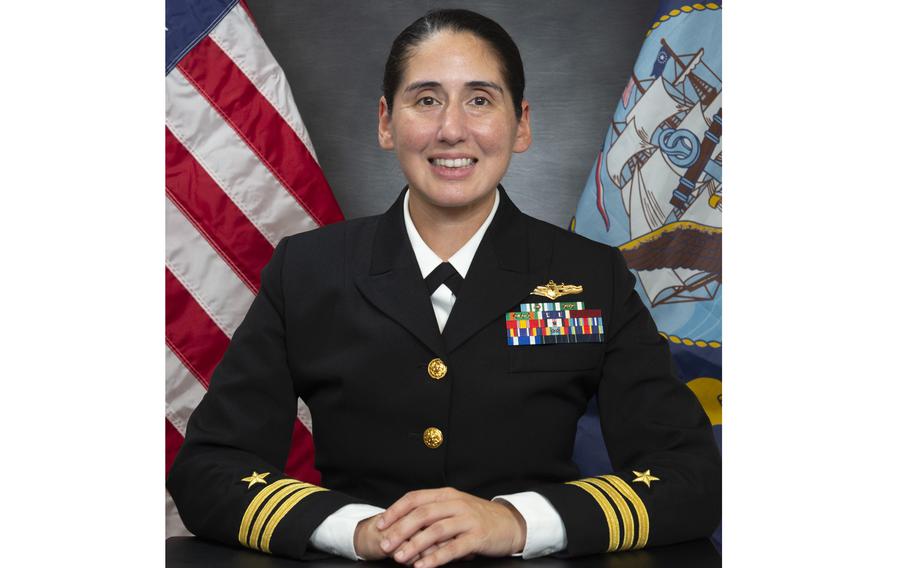 Cmdr. Sarah M. Quemada in uniform, with the American flag behind her, in an official Navy portrait.