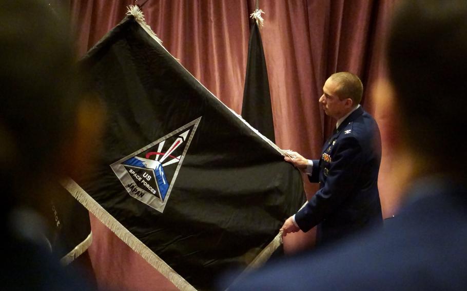 A colonel unfurls the unit’s flag during an activation ceremony.