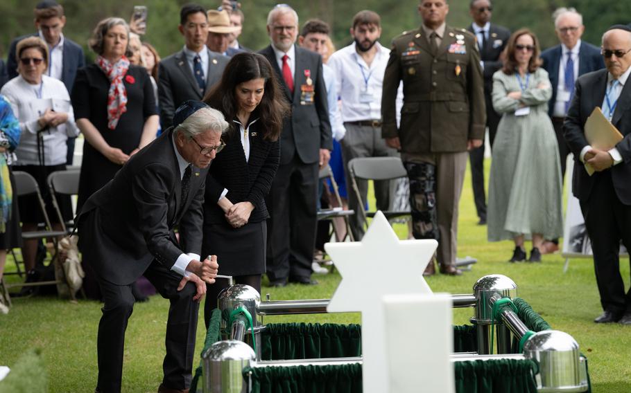 Steward Sadowsky, left, and Samantha Baskind, relatives of 1st Lt. Nathan Baskind, lower the soldier’s casket into the ground at Normandy American Cemetery in Colleville-sur-Mer, France, on June 23, 2024.