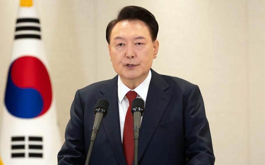 South Korean President Yoon Suk Yeol speaks into a microphone while standing in front of a South Korean flag.