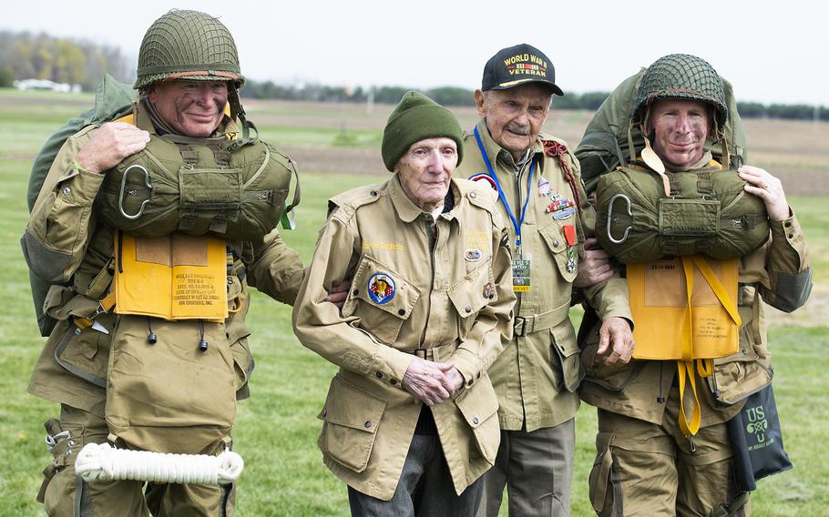 WWII airborne demonstration team members walk with WWII veterans Jim “Pee Wee” Martin, center left, and Dan McBride as they exit the drop zone during a 100th birthday celebration held in Martin’s honor, April 23, 2021, in Xenia, Ohio. Both McBride and Martin, served as paratroopers assigned to 101st Airborne Division out of Fort Campbell, Kentucky.