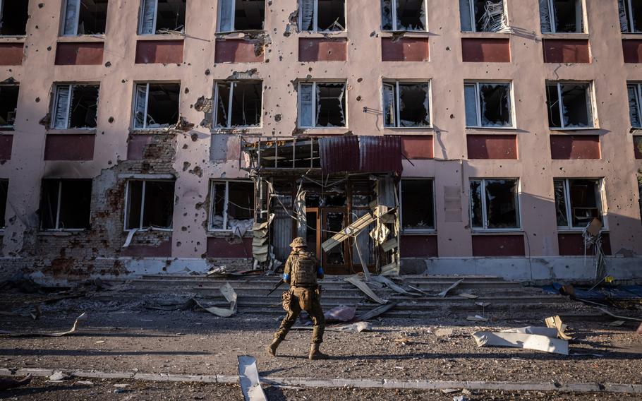 Ukrainian soldiers walk past a building hit by shrapnel in the Ukraine-controlled city of Sudzha, Russia, on Saturday.