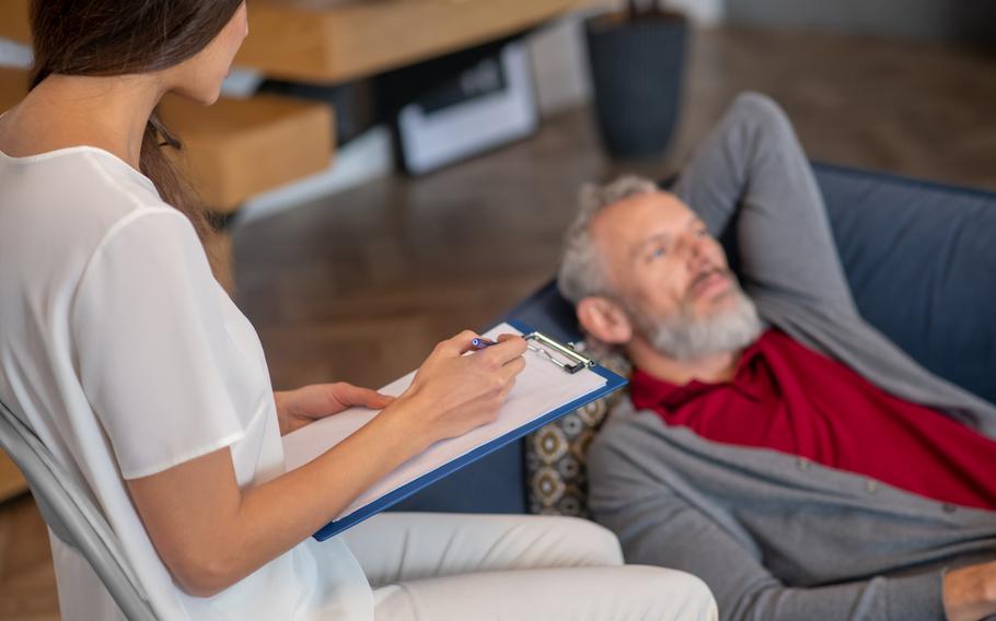 A grey-haired man talking to the professional psychotherapist