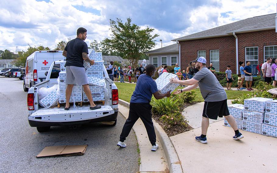 Three men unload relief supplies from the bed of a pickup truck.