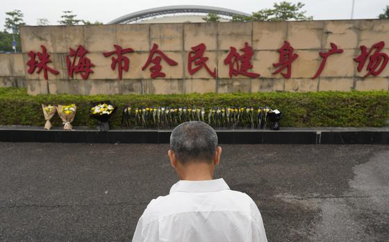 FILE - A man stands near flowers laid outside the "Zhuhai People's Fitness Plaza" where a man rammed his car into people exercising at the sports center, in Zhuhai in southern China's Guangdong province, Nov. 13, 2024. (AP Photo/Ng Han Guan, File)