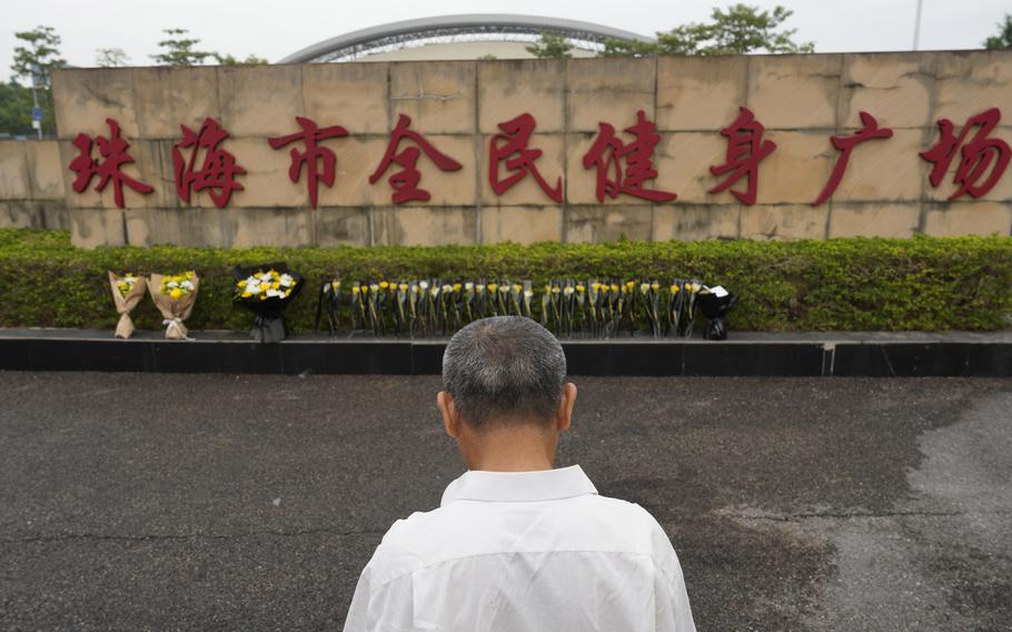 A man stands near flowers laid outside the “Zhuhai People’s Fitness Plaza” 