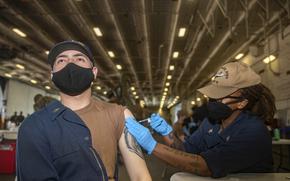 A sailor receives a COVID-19 vaccination in USS Gerald R. Ford’s hangar bay in May 2021. Sailors who refused the COVID-19 vaccine on religious grounds and had adverse actions taken by the Navy as a result can have their records corrected, according to the terms of a lawsuit settlement reached last week.