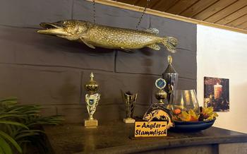 A mounted pike fish and trophies decorate a wall.