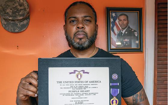 Raffique Khan, who served three tours in Afghanistan, holds his Purple Heart medal and certificate at his home in Queens.