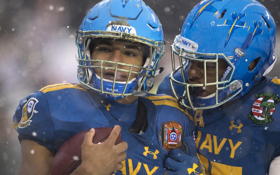 Navy players during the 2017 game wear sleek blue uniforms with gold trim and F/A-18 Hornet fighter jets on the helmets.