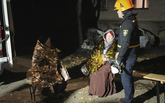 In this image provided by the Ukrainian Emergency Service on Monday, Nov. 11, 2024, a rescuer-psychologist, right, talks to local residents in a yard of residential area after a Russian attack in Mykolaiv, Ukraine. (Ukrainian Emergency Service via AP)