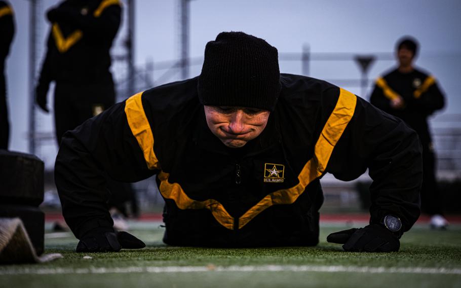 A soldier wearing a PT uniform does hand release pushups during a fitness test.