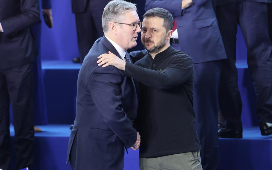 British Prime Minister Sir Keir Starmer shakes hands with and speaks into the ear of Ukrainian President Volodymyr Zelenskyy, Nov. 7, 2024.