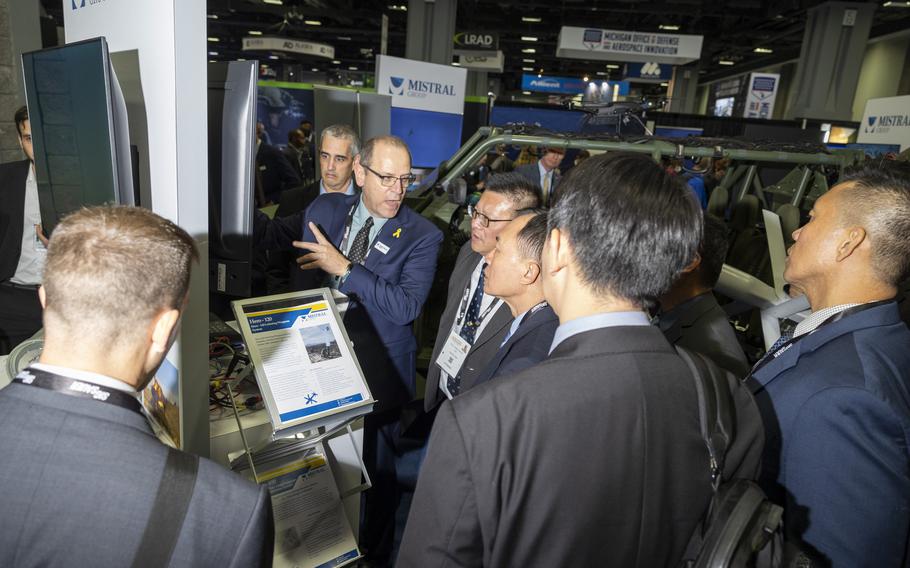 A booth attendant at Mistral speaks with attendees