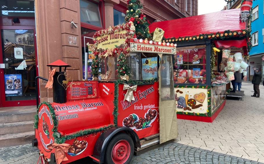 A red chestnut stand that looks like a train with green garlands on it is part of the festivities at the Kaiserslautern Christmas market.