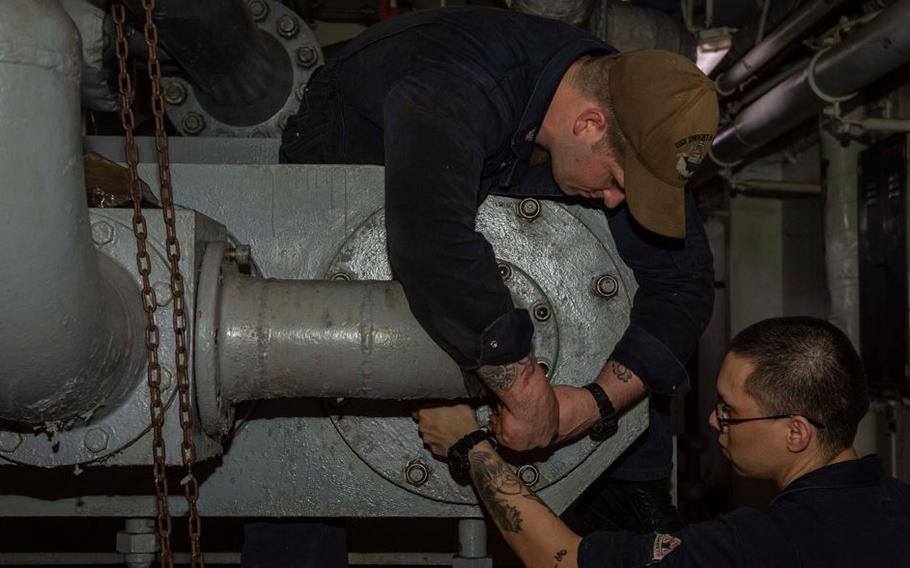 Petty Officer 1st Class Victor Herring Logam, left, and Petty Officer 2nd Class Luis Guzman remove a pipe from an aircraft elevator hydraulic pump aboard the aircraft carrier USS Dwight D. Eisenhower in the Arabian Sea, on May 28, 2021. 