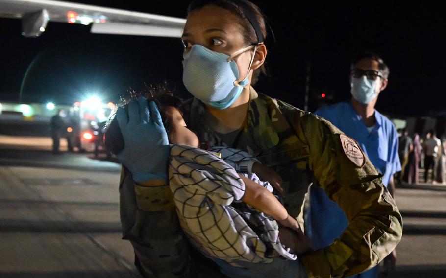 U.S. Air Force Tech. Sgt. Angie Smith carries a sleeping baby down from an Airbus A320 aircraft carrying evacuees from Afghanistan to Naval Air Station Sigonella, Italy, Aug. 29, 2021. 