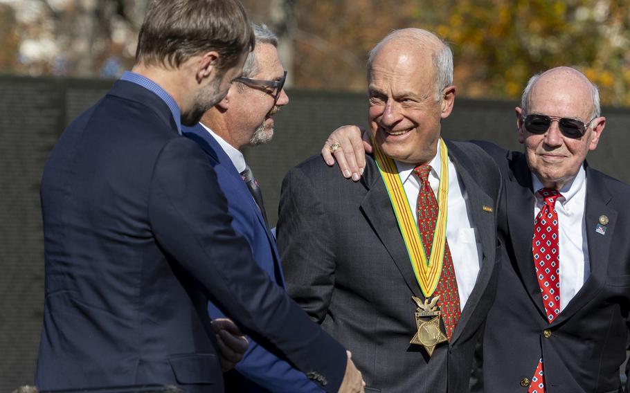 A man wearing a medal shakes hands with other men.