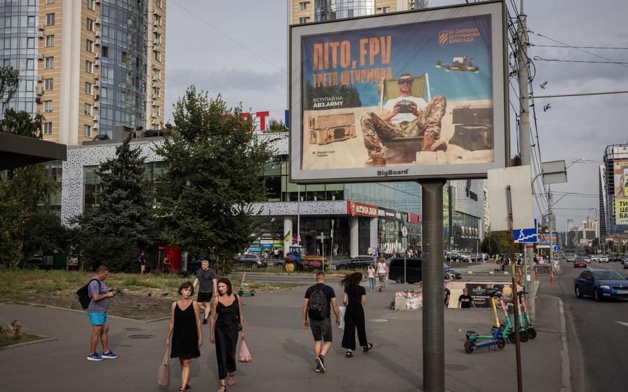 A recruitment sign in Kyiv reads “Summer, FPV, Third Assault.”