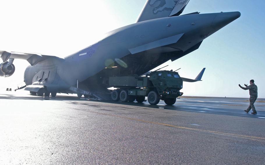 A pilot controls a High Mobility Artillery Rocket System (HIMARS) from the rear of a C-17 Globemaster III.