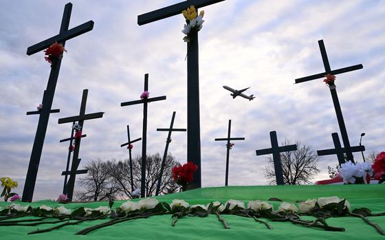 A commercial airplane takes off from Ronald Reagan International Airport  past crosses and flowers at a memorial near the airport on Feb 2, 2025. (Roberto Schmidt/AFP/Getty Images/TNS)