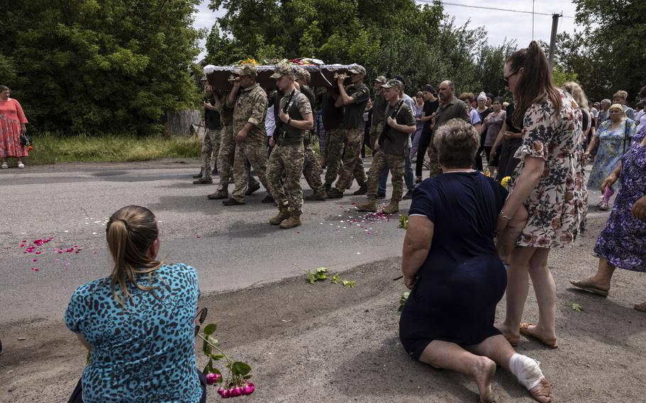 Mourners kneel as Ukrainian soldiers carry the coffin of Ukrainian soldier Oleksandr Babych in Krasnosillia, Ukraine, during his funeral on June 24, 2023.