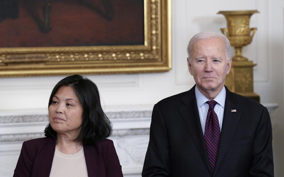 Joe Biden stands beside the acting secretary of labor in a white-walled room.