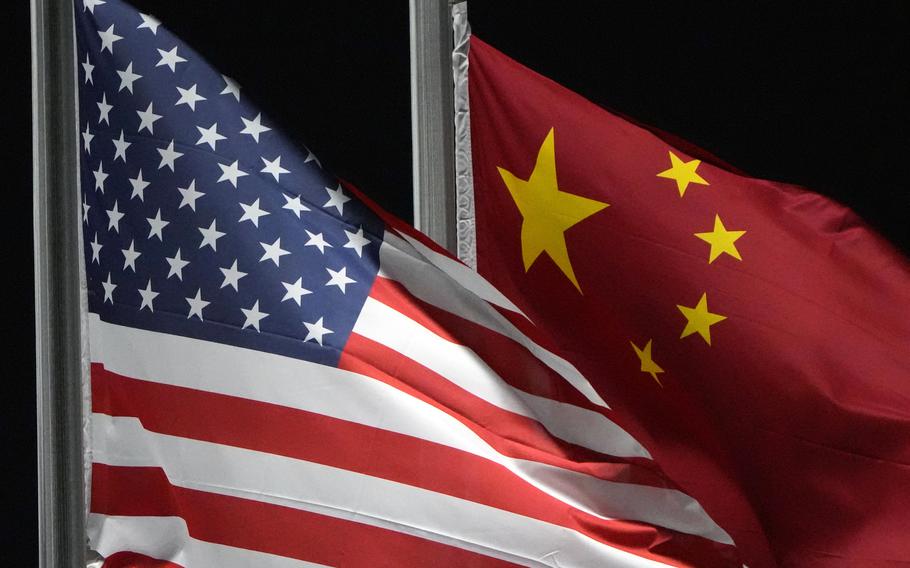 A U.S. flag and a Chinese flag flutter next to each other on flagpoles.