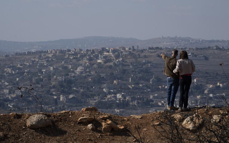 An Israeli couple looks out on damaged buildings.