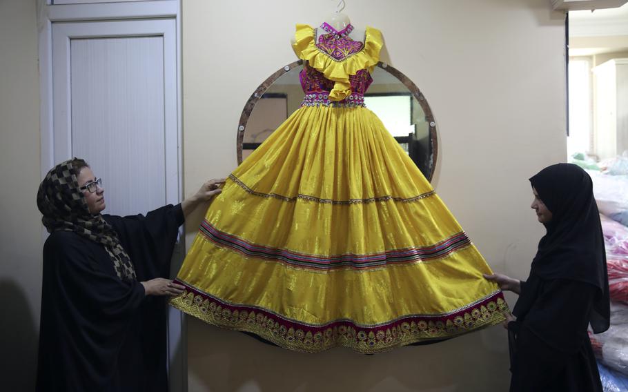 Afghan women tailors display a dress in the Afghan Women Business Hub in Kabul, Afghanistan, Tuesday, July 2, 2024. Half of Afghanistan’s population now finds itself locked out of the freedom to work at a time when the country’s economy is worse than ever, with few jobs available to women in the country. 