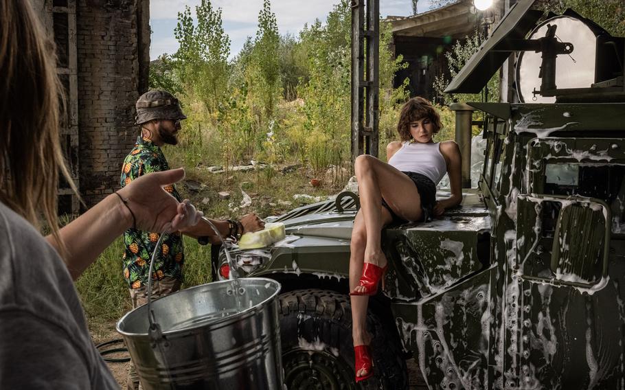 Maria, a model sits on the hood of a Humvee for a photography session.