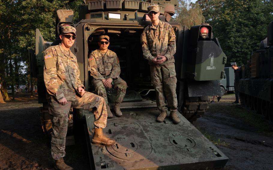 Spc. Andrew Evatt, left, Spc. Tyrese Cooley and Spc. Michael Lineberry pose for photos outside their Bradley Fighting Vehicle ahead of the Tanks in Town parade in Mons, Belgium, Sunday, Sept. 1, 2024. The soldiers, assigned to 2nd Battalion, 5th Cavalry Regiment, 1st Armored Brigade Combat Team, 1st Cavalry Division, traveled from Poland to participate in the event.