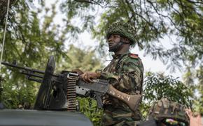 A soldier adjusts a machine gun mounted on a vehicle.