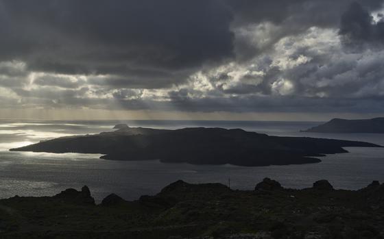 Sun rays illuminate the volcanic islet of Nea Kameni, part of the earthquake-struck island of Santorini, Greece, Tuesday, Feb. 4, 2025. (AP Photo/Petros Giannakouris)