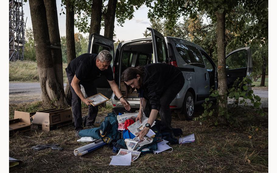 Yuriy Savchuk, director of Ukraine’s war museum, (left) packs items taken by Ukrainian soldiers from inside Russia into a van in Yunakivka on Friday.